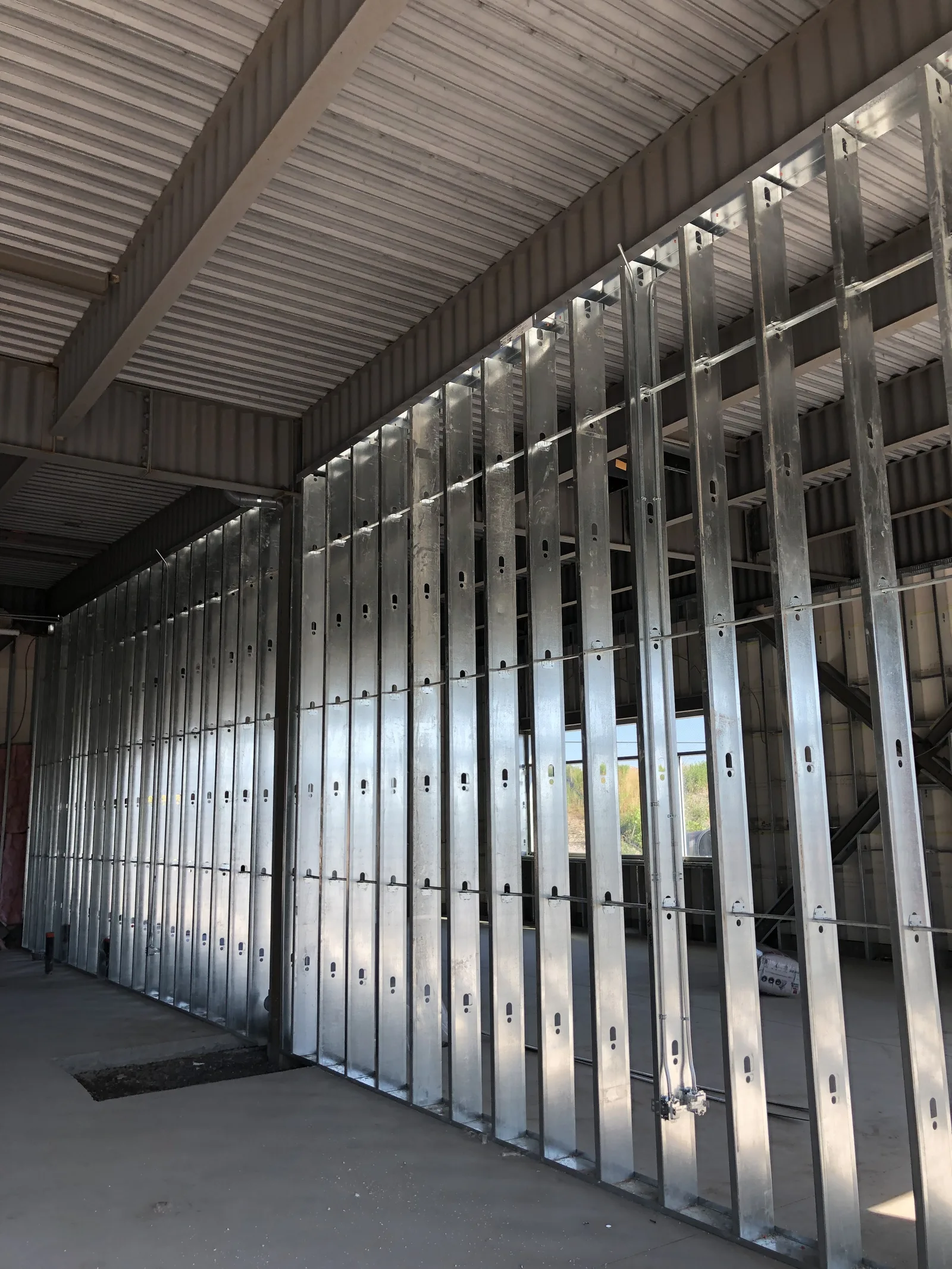 Tall steel stud framing under an open-web steel roof
