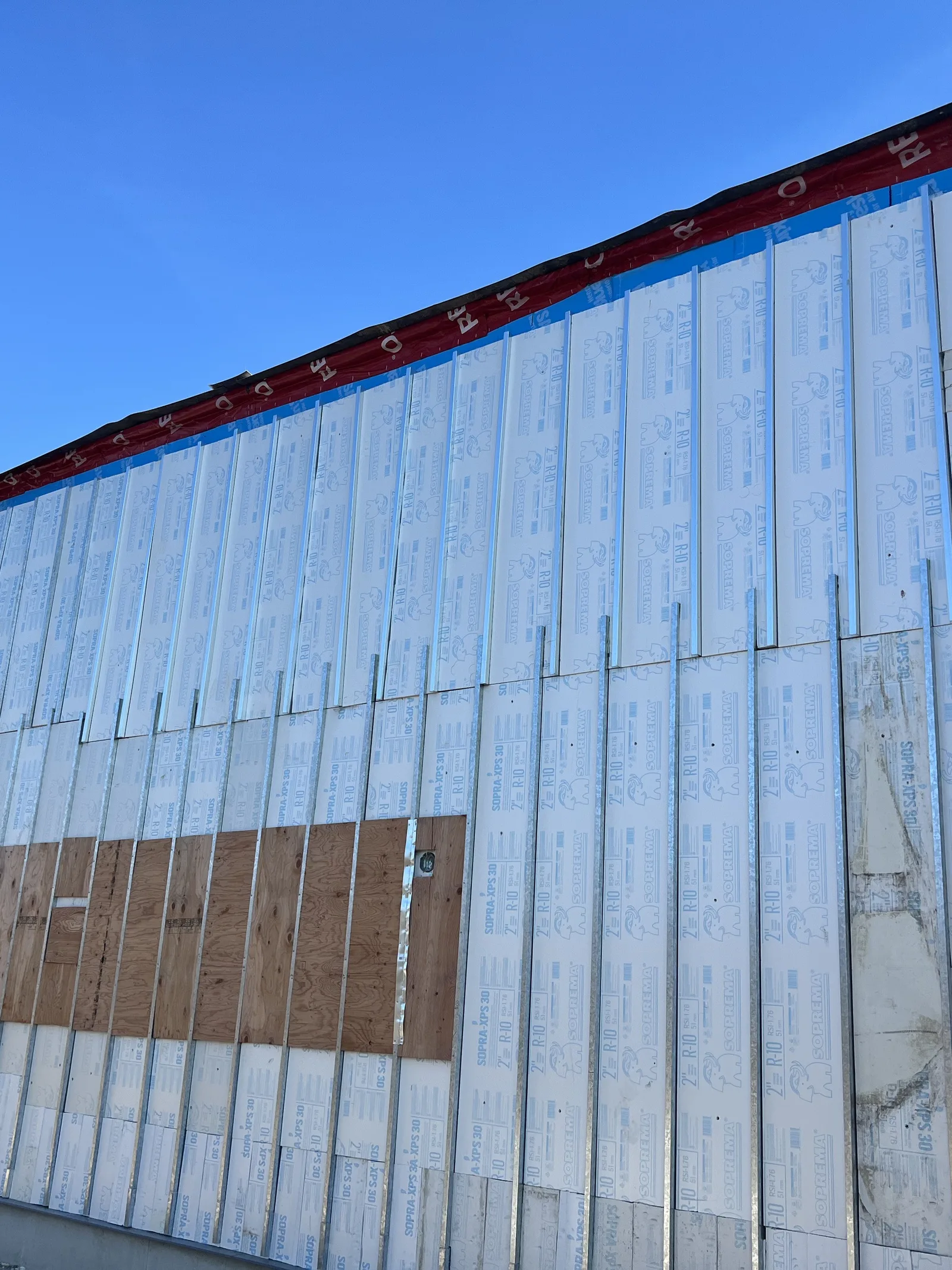 Exterior wall with rigid board insulation fastened over steel studs