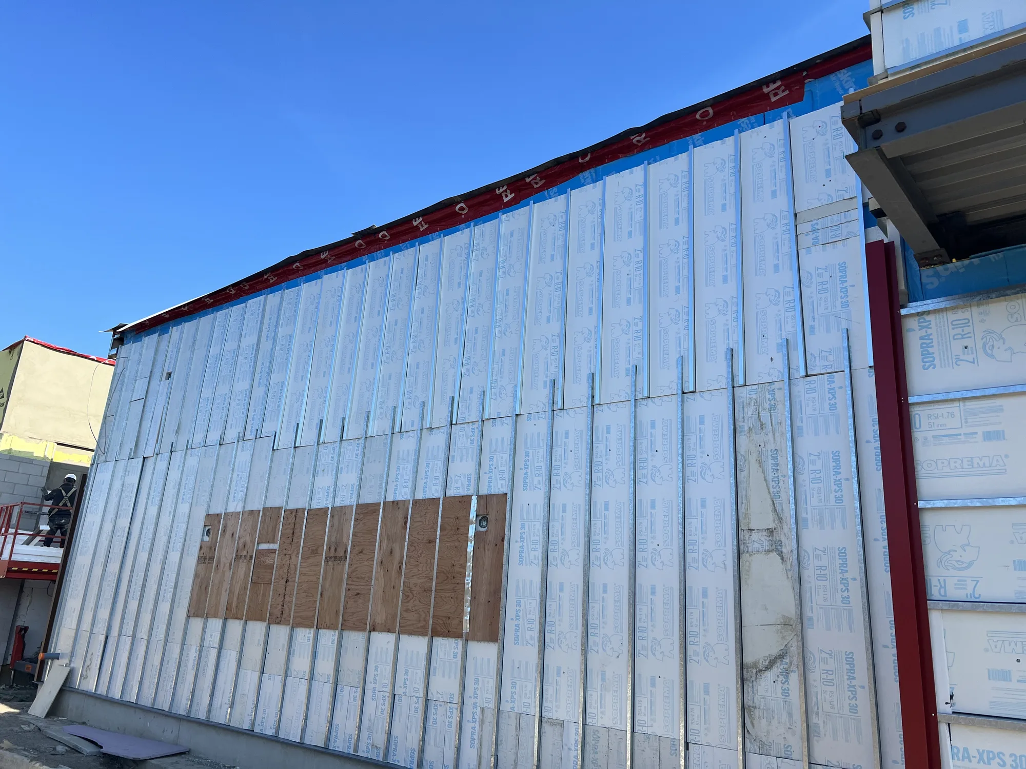Exterior wall with rigid board insulation fastened over steel studs